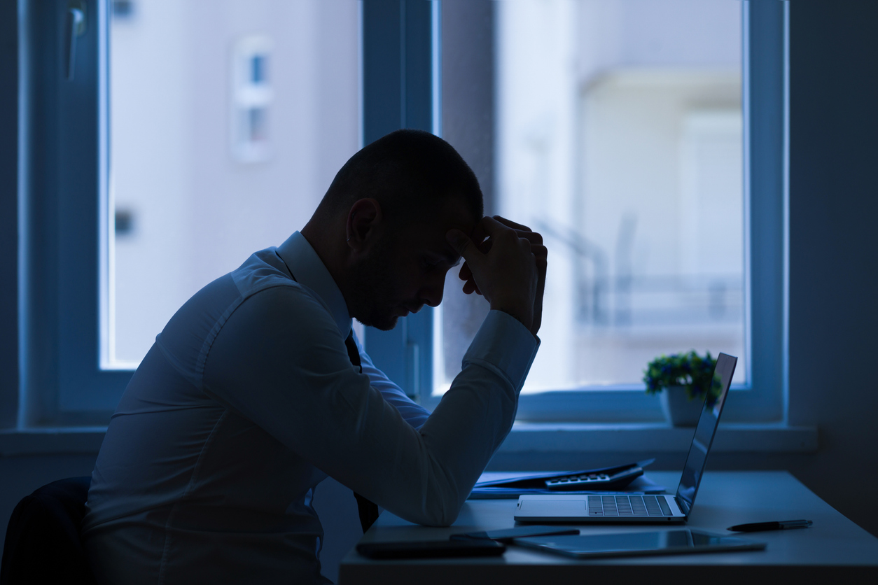 A person sitting at a desk with his head in his hand

Description automatically generated